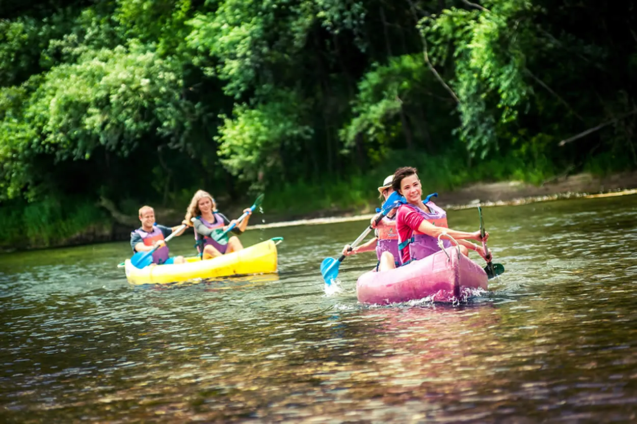 Grupo practicando kayak en un río rodeado de bosque, una actividad de turismo activo en el occidente de Asturias